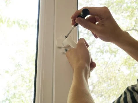 A man fixes a window, fastens a handle close up Stock Photos