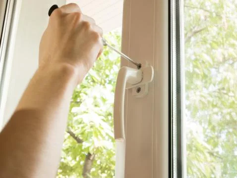 A man fixes a window, fastens a handle close up Stock Photos