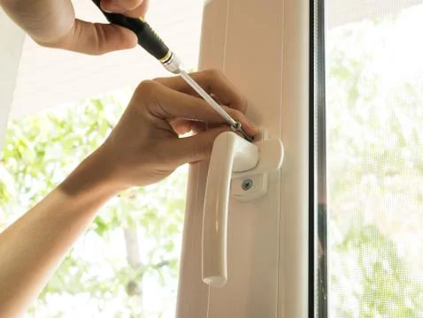 A man fixes a window, fastens a handle close up Фото