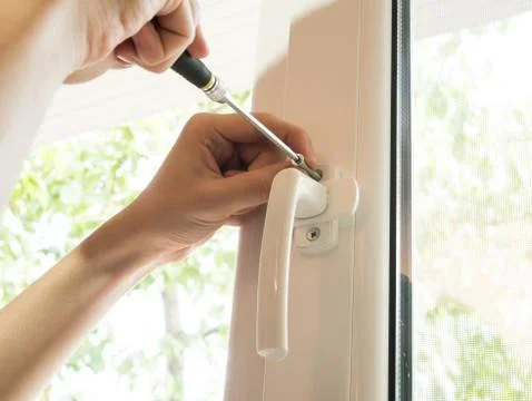 A man fixes a window, fastens a handle close up Stock Photos