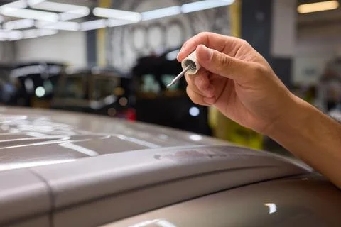 Man fixing car scratch precisely in repair shop, displaying craftsmanship in  Stock Photos
