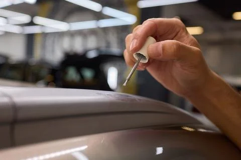 Man fixing car scratch precisely in repair shop, displaying craftsmanship in  Stock Photos