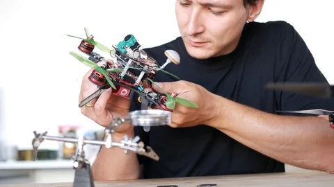 Man fixing a crashed drone. Quadrcopter service laboratory. 4K Stock Footage 90451349