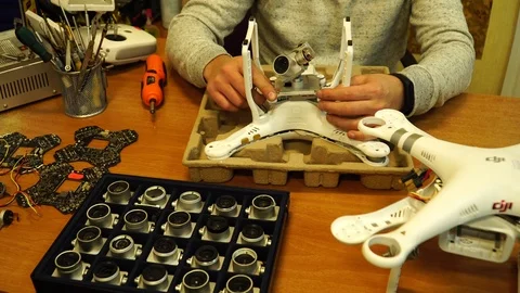 Man fixing a crashed drone. Quadrocopter service laboratory. 4K Stock Footage 86912119