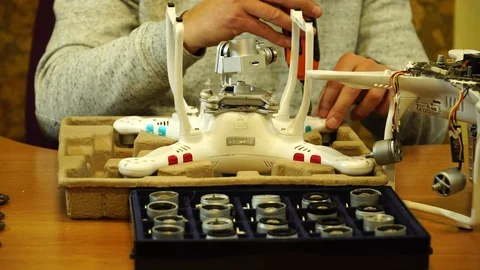 Man fixing a crashed drone. Quadrocopter service laboratory. 4K Stock Footage 86912147