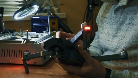 Man fixing a crashed drone. Quadrocopter service laboratory. Tracking shot. 4K Stock Footage 86914837