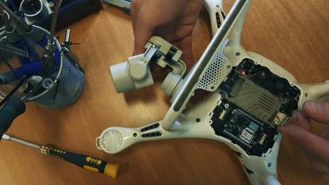 Man fixing a crashed drone. Quadrocopter service laboratory. 4K Stock Footage 86916039
