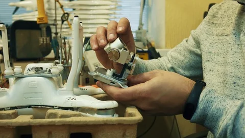 Man fixing a crashed drone. Quadrocopter service laboratory. Tracking shot. 4K Stock Footage 86916431