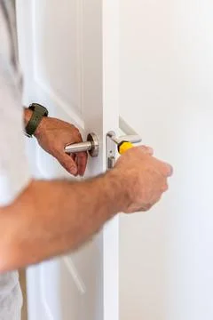 Man fixing door handle with screwdriver doing home repair Stock Photos