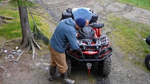 Man is fixing a four wheeler on a camping site in Canada forest Stock Footage 130155439