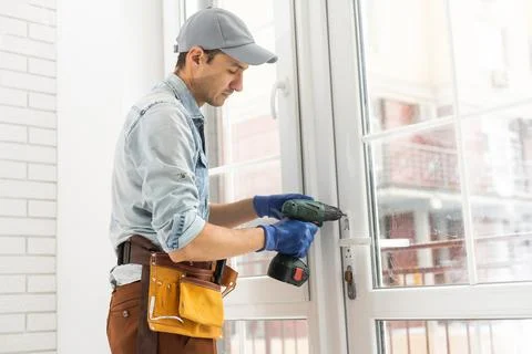 Man fixing lock to window with electric screwdriver Stock Photos