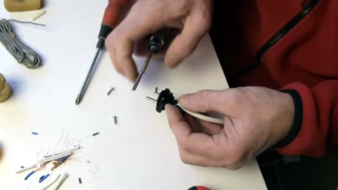 A man is fixing an outlet. Inserts the wires into the socket. Stock Footage 146789486