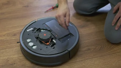 A man is fixing robot vacuum cleaner by hand Stock Footage 255227252