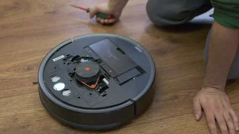 A man is fixing robot vacuum cleaner by hand Stock Footage 255227327