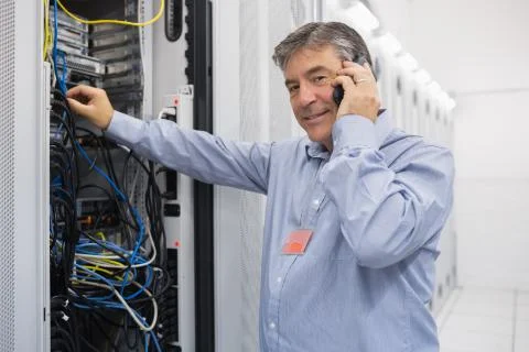 Man fixing server wires and talking on phone Stock Photos