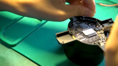 A man fixing a small part of a digital holographic fan while the machine is Stock Footage 96225475