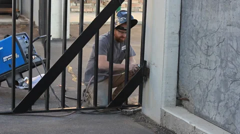 MAN FIXING WELDING A GATE OUTSIDE Stock Footage 32637191