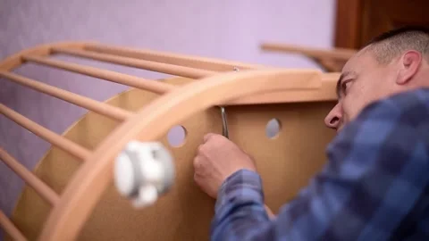 Man fixing wooden  crib bed, preparation for the appearance of a newborn child.B Stock Footage 246229937