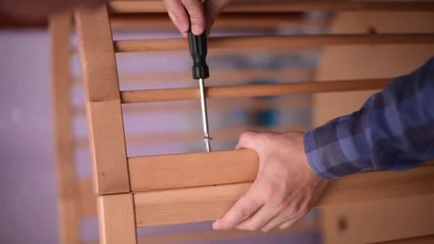 Man fixing wooden  crib bed, preparation for the appearance of a newborn child.B Stock Footage 246229946