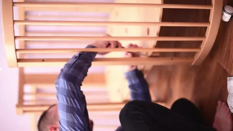 Man fixing wooden  crib bed, preparation for the appearance of a newborn child.B Stock Footage 246229949