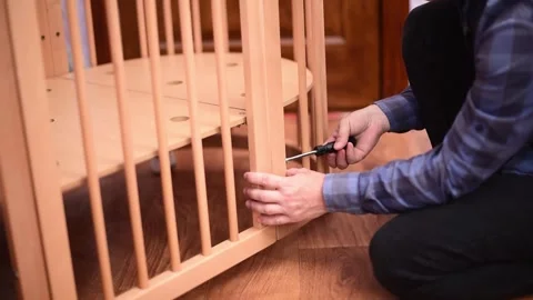 Man fixing wooden  crib bed, preparation for the appearance of a newborn child.B Stock Footage 247132236