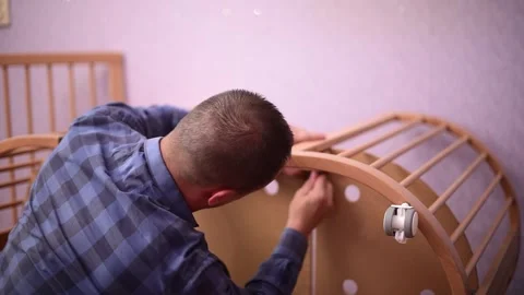 Man fixing wooden  crib bed, preparation for the appearance of a newborn child.B Stock Footage 247132237