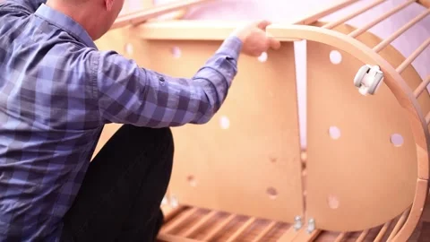 Man fixing wooden  crib bed, preparation for the appearance of a newborn child. Stock Footage 247327150