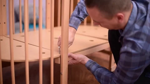 Man fixing wooden  crib bed, preparation for the appearance of a newborn child.B Stock Footage 250072886