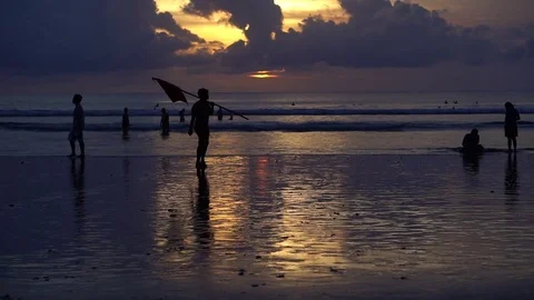The man with the flag is on the shore of the ocean at sunset Video stock 71580725