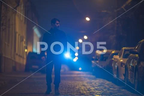 The man with a flashlight inspect the street. Evening night time Stock Photos