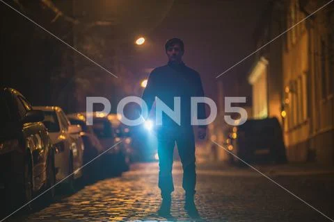 The man with a flashlight inspect the street. Evening night time Stock Photos