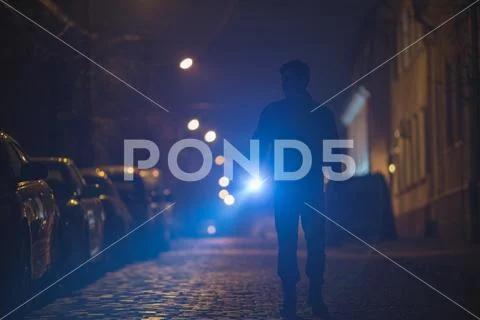 The man with a flashlight inspect the street. Evening night time Stock Photos