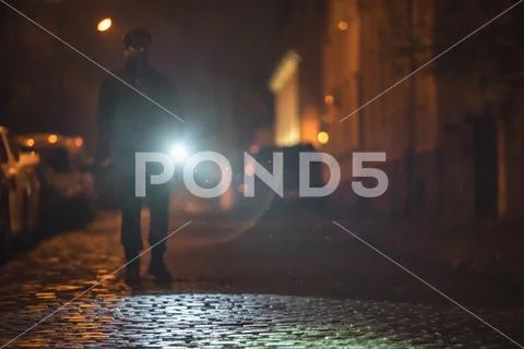 The man with a flashlight stand on the road. Evening night time Stock Photos