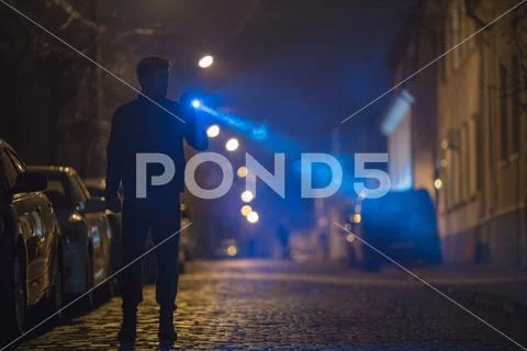The man with a flashlight stand on the road. Evening night time Stock Photos