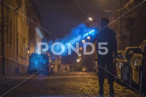 The man with a flashlight stand on the road. Evening night time Stock Photos