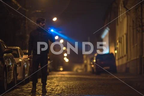 The man with a flashlight stand on the road. Evening night time Stock Photos