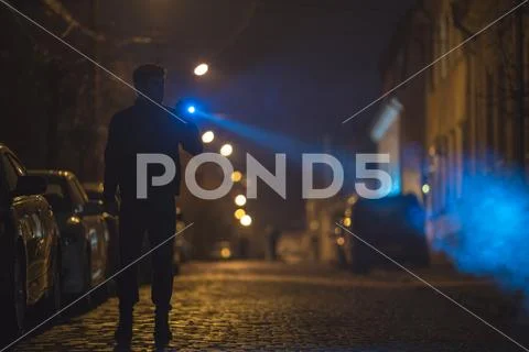 The man with a flashlight stand on the road. Evening night time Stock Photos
