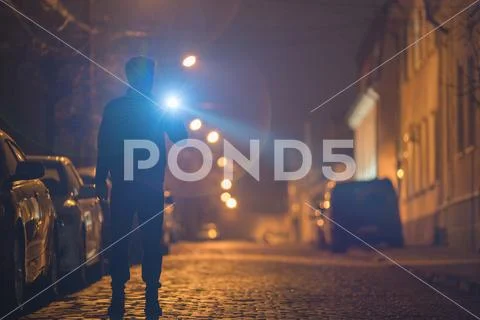 The man with a flashlight stand on the street. Evening night time Stock Photos
