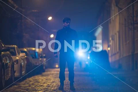 The man with a flashlight stand on the street. Evening night time Stock Photos