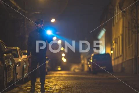The man with a flashlight stand on the street. Evening night time Stock Photos