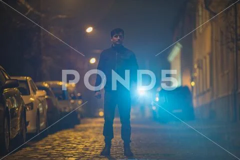 The man with a flashlight stand on the street. Evening night time Stock Photos