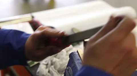 Man with flat file thin out piece of steel in a vice Stock Footage 64120460