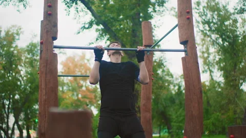 Man flexes outdoors, He completes pullup confidently outside, Determined man Stock Footage 325033989