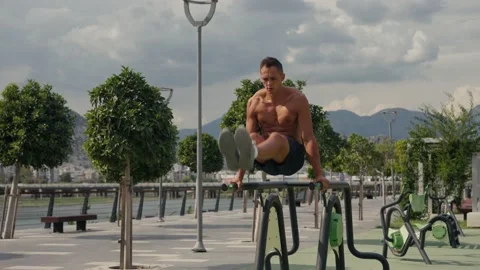Man flexing abs on parallel bars in gym. Working on his core. Full length shot Video stock 218204538