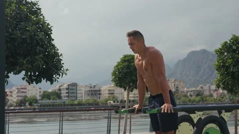 Man flexing abs on parallel bars in gym. Working on his core. Full length shot Video stock 218204746
