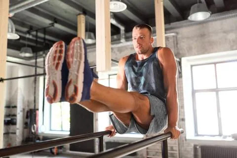 Man flexing abs on parallel bars in gym Stock Photos