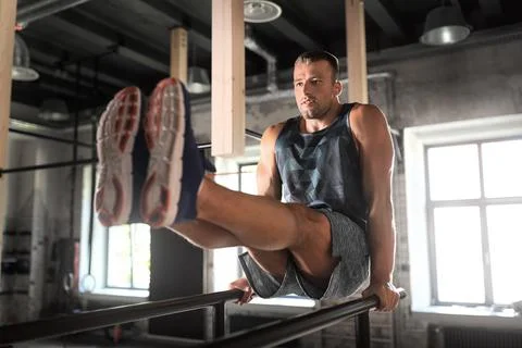Man flexing abs on parallel bars in gym Stock Photos