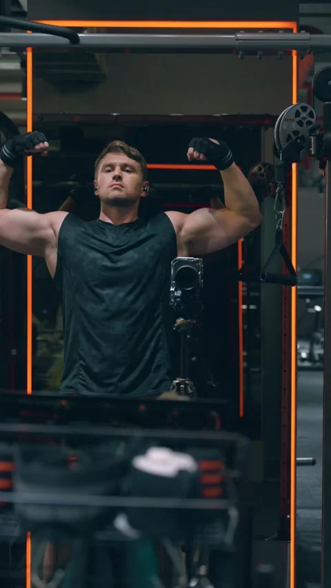 Man Flexing Biceps While Filming Himself in Gym Mirror Stock Footage 340888948