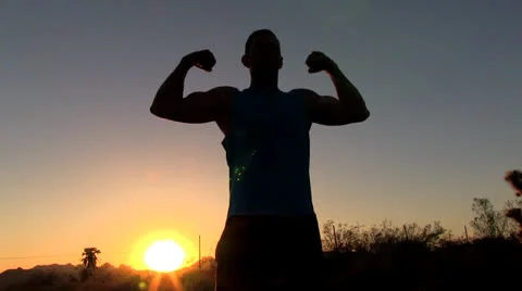 Man flexing muscles in desert sunset. 스톡 동영상 24811732