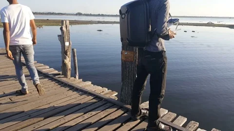 Man flies drone on U Bein Bridge, shot from behind, Taungthaman Lake, Mandalay Видео 79622894